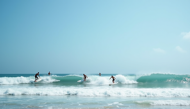 Eye-level view of surfers catching waves at Manly Beach with clear blue sky